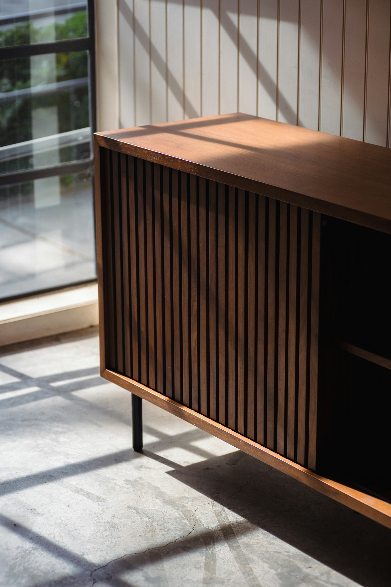 A walnut sideboard with fluted doors in raking afternoon sun