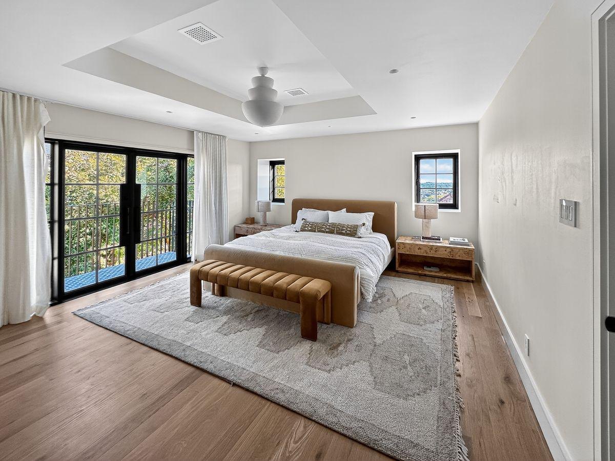 After: a pale bedroom with oak floors and black French doors