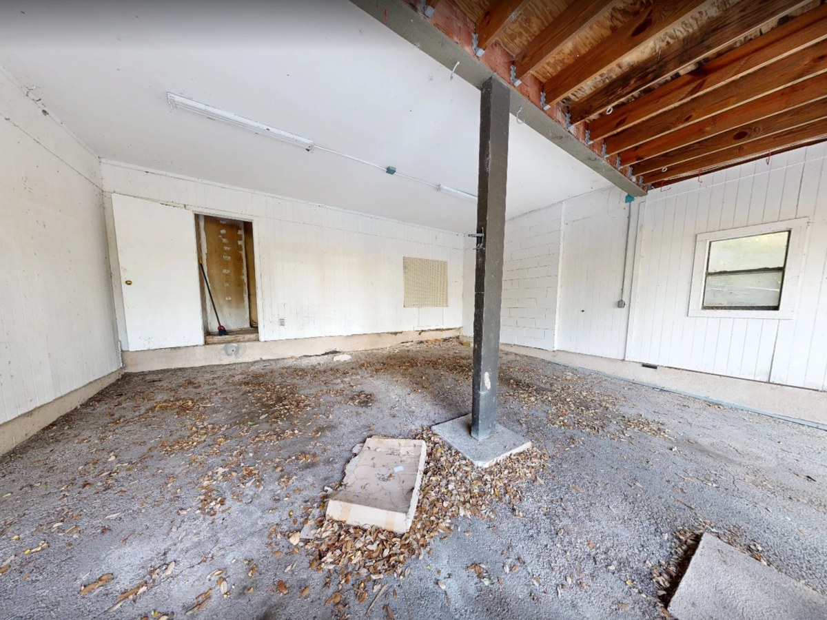 Before: a garage with a concrete floor, a steel post and open joists