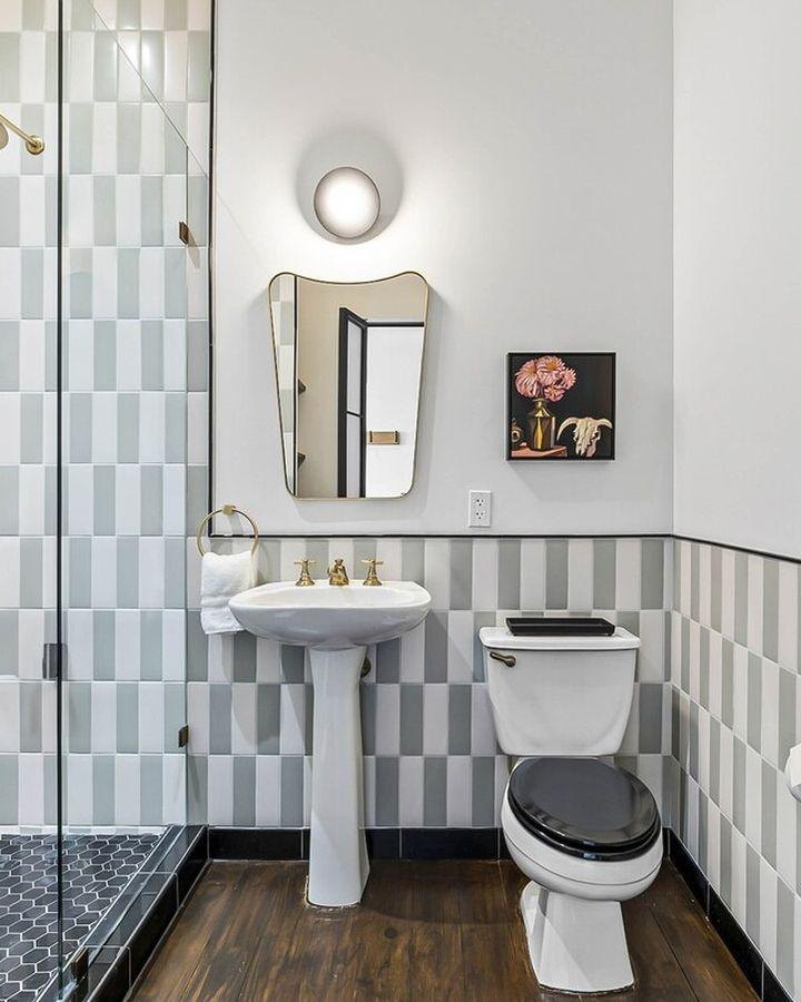 After: the same bath with a walk-in shower, stacked tile and a brass-trimmed mirror
