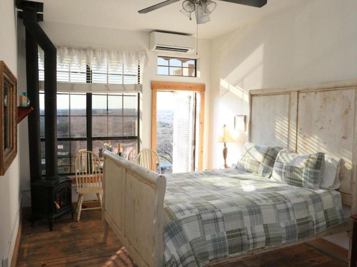 Before: a guest room with a quilted bed, a twig headboard and a wood stove