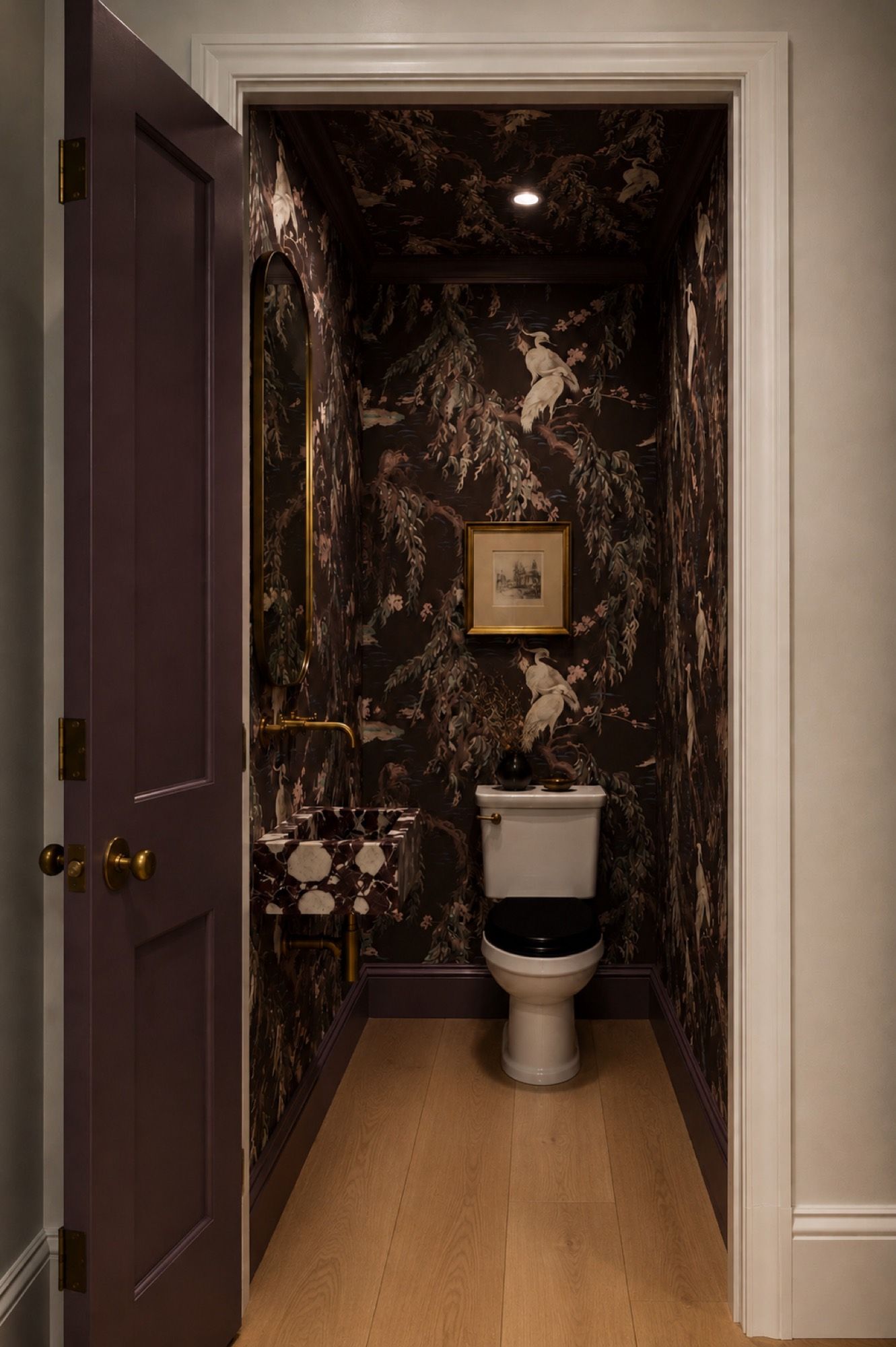A powder room papered in dark crane wallpaper
