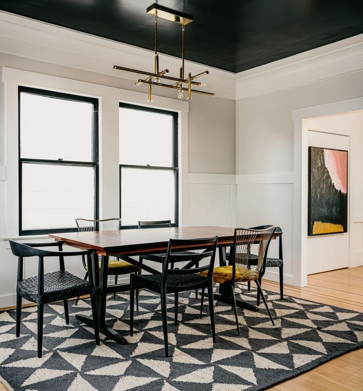 A dining room under a black ceiling with a brass chandelier