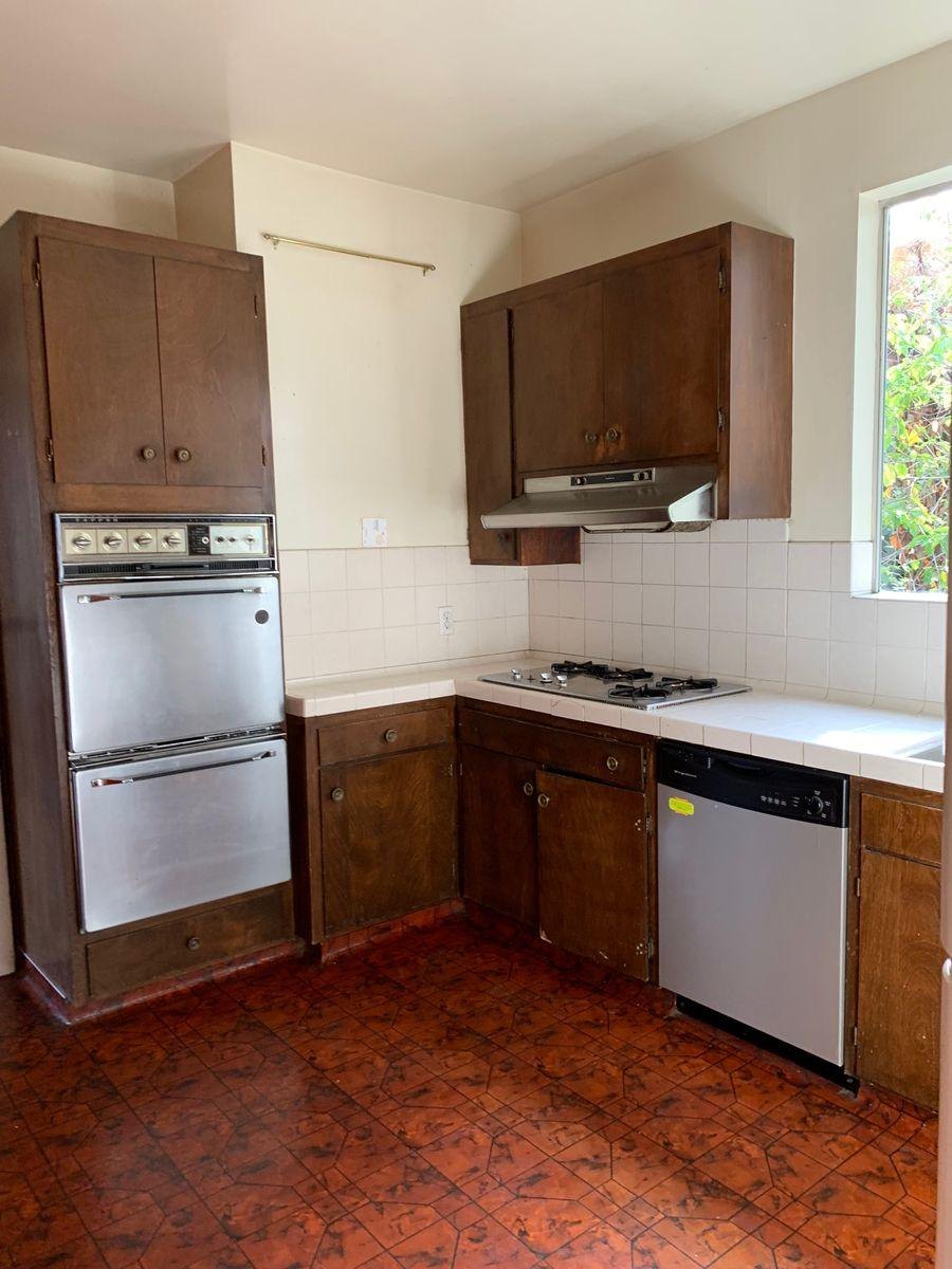 Before: dark wood cabinets, wall ovens and a red floor