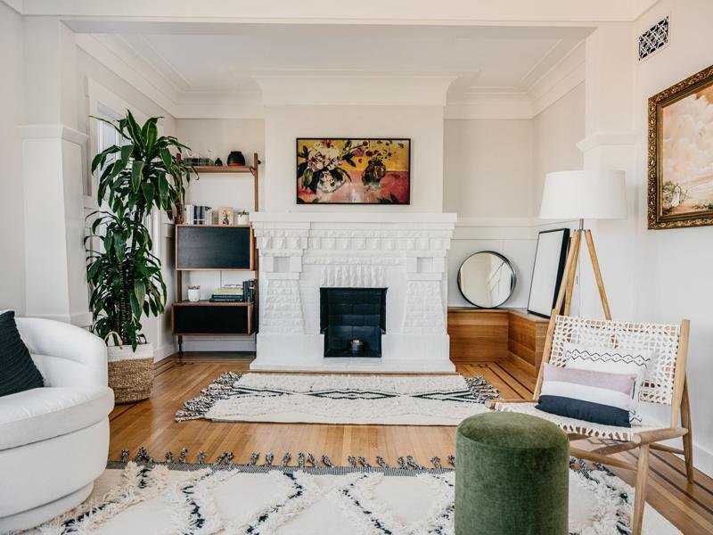 A living room with a white painted fireplace and a pale rug