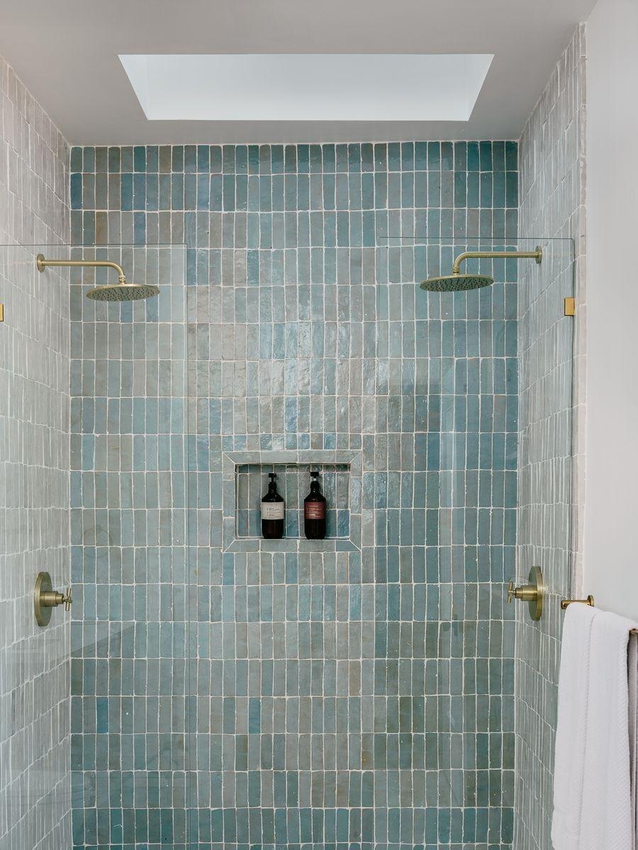 After: a shower in blue-green glazed tile with brass fittings